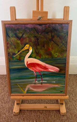 Oil painting of a pink wading bird with yellow beak standing in shallow water on wooden easel