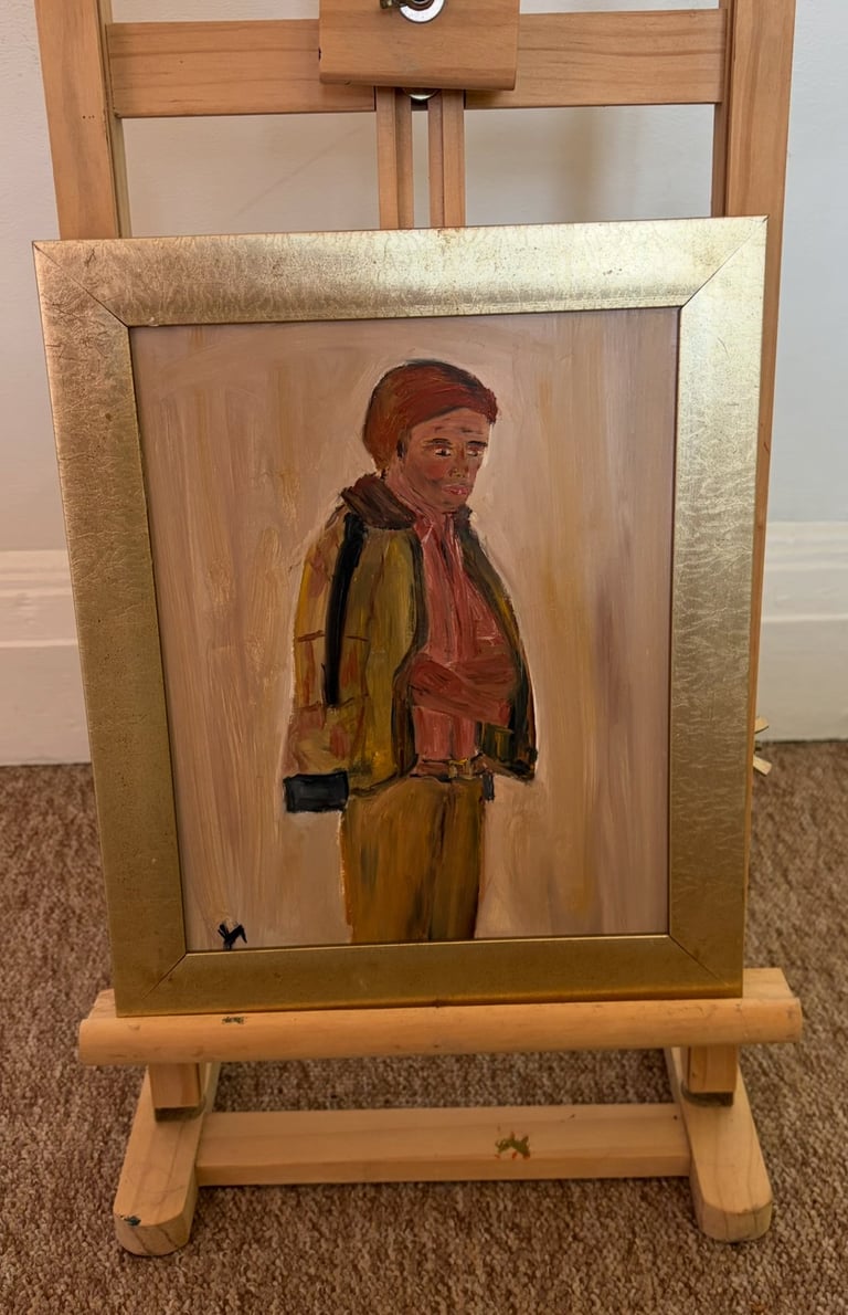 Oil painting of a man in a red hat and yellow jacket on an easel with gold frame