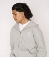 Person wearing a light gray zip-up hoodie over a white shirt, shown in profile view against a neutral background