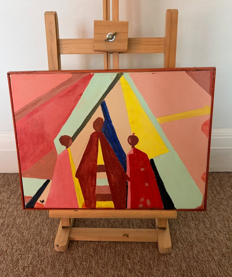 Abstract painting on wooden easel featuring geometric shapes and figures in red, yellow, blue, and green on a coral background