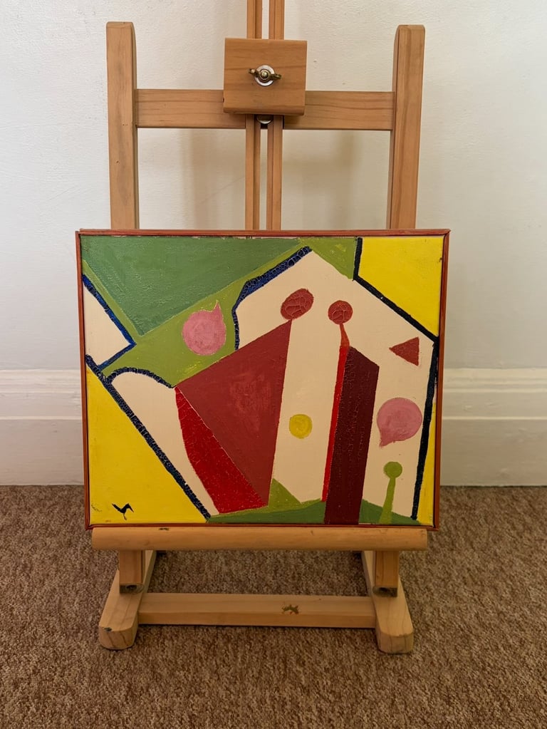 Wooden easel displaying an abstract painting with geometric shapes in red, green, yellow, and cream colors with colored dots