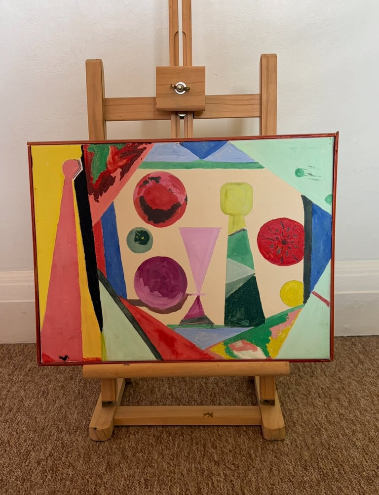 Abstract colorful painting on easel featuring geometric shapes, circles, and vibrant red, yellow, blue, and green colors